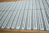 Secured edge of vintage Moroccan Kilim rug showing vertical charcoal geometric stripes.