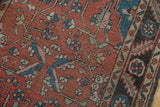 Vintage Heriz rug detail: madder root red field, pinwheel motifs, and navy border.