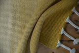 Thick braided ivory fringe on the saffron yellow Moroccan rag rug.