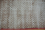 Detailed view of worn ivory, red, and charcoal Sparta rug, revealing exposed foundation and red selvage.