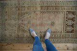 Vintage distressed Oushak runner, dusty rose prayer design, worn texture, with feet.