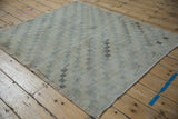Distressed surface showing checkered lattice pattern in ivory, beige, and slate colors.
