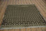 Distressed Oushak rug's lower border showcasing geometric starburst motifs in time-softened brown and ivory.