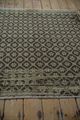 Distressed vintage Oushak rug border with chocolate brown geometric panels and ivory selvage.