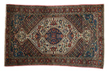 Vintage Baktiari rug with a tiered medallion and floral patterns in indigo, cherry red, and ivory.
