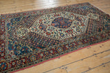 A full perspective of the vintage Bakhtiari rug's concentric medallion, indigo corners, and cherry red border.
