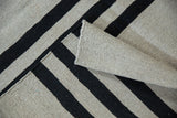 Handwoven Pakistani Kilim rug fold, highlighting silver and charcoal horizontal stripe design.
