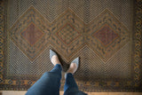 Antique Afshar rug: triple concentric medallions, zigzag field in camel, navy, and red tones.