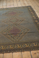 Tattered side and geometric border of antique Afshar rug, with camel, navy, and green motifs.