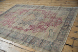 Vintage Turkish Kaisary rug seen at an angle, showing its floral medallion and time-softened wear.