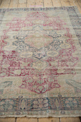 Angled view of a vintage Kaisary rug showing its time-softened pile and faded floral design.