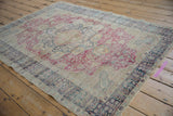 Angled perspective of a vintage Turkish Kaisary rug showing its worn, low pile and floral design.
