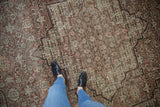 Overhead view of the distressed, low-pile texture of a vintage Tabriz carpet for scale.