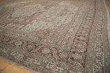 Low-angle view of a vintage Tabriz rug's corner, detailing the serrated leaf and floral main border.
