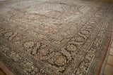 Angled view of a vintage Tabriz carpet's corner, showing the detailed floral border and low pile texture.
