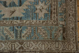 Distressed geometric border of a vintage Northwest Persian runner in blue, beige, and time-softened brown.