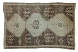 Distressed Kars carpet, primitive triple medallion with subtle abrash in neutral beige and brown.