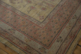 Khotan design carpet corner with dusty gold field and pomegranate motifs meeting a cochineal red border.