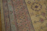 Dusty gold field with pomegranate motifs and abrash, bordering pale cochineal red patterns.