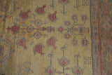 Dusty gold abrash field with pale red pomegranate and floral vase motifs, showing border.