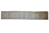 Distressed Pakistani Khotan runner, roundel medallion, open beige field, scrolling border design.
