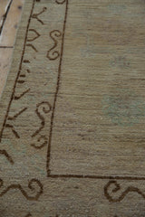 Distressed Pakistani Khotan design runner's scrolling ram's horn brown border on a beige field.
