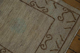 Distressed beige pile texture and brown scrolling ram's horn border of Khotan runner.