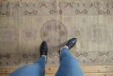 Distressed Khotan runner, visible faded mauve medallions and scrolling brown border.