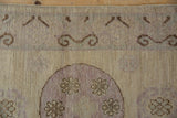 Time-softened beige, mauve, and chocolate brown Khotan rug with ram's horn border and medallion.