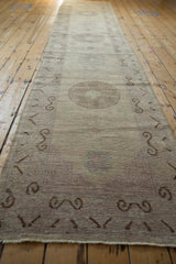 Distressed Pakistani Khotan runner, beige mauve field, chocolate brown scrolling border, pile wear.