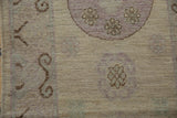 Distressed beige and mauve Khotan runner texture, showing faded medallions and visible knot heads.