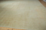 Corner of vintage distressed Oushak carpet showcasing faded beige, ivory, and blush floral patterns.