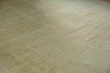 Subtle beige and blush floral outlines on a vintage distressed Oushak carpet with even wear.