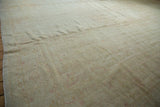 Worn knot heads and faint patterns on a vintage distressed Oushak rug in soft gold and blush.