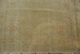 Low pile of vintage distressed Oushak carpet, with faint blush and gold floral motifs.