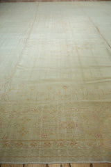 Faint blush floral outlines on the distressed low pile of this vintage Oushak carpet.