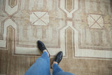 Person's feet on a vintage hand-knotted Kars carpet, heavily abrashed with ivory geometric palmettes.