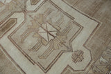 Close-up of a vintage Kars carpet showing simplistic palmette drawing with abrashed beige and brown pile.