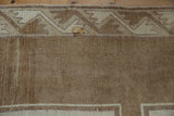 Vintage Kars carpet's abrashed beige field detail with geometric main border and subtle stain.