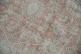 Meandering dusty rose and ivory floral cross-section motif on a distressed vintage Sparta carpet.