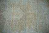 Distressed Mahal carpet texture showing exposed foundation with beige and dusty blue tones.