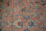 Textural close-up of distressed Mahal carpet's rose, teal, beige vinery and palmettes.