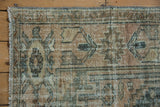 Fringes and distressed pile of a vintage Hamadan rug, showing faded ivory, brown, and teal motifs.