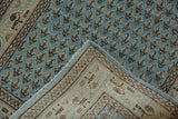 Folded vintage Mir Sarouk runner, showing distressed dusty blue pile and woven geometric Serbend border.