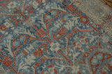 Worn, hand-knotted texture showing the floral vinery in powder blue and terracotta red.