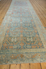 The repeating terracotta and powder blue pattern of a long, distressed vintage Hamadan rug runner.