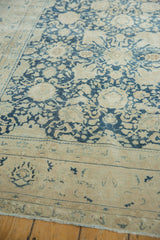 Textured detail of distressed Tabriz carpet, faded denim blue Safavid patterns on worn ivory field.