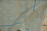 Textured pile with blue serrated leaf border on a distressed vintage Hamadan rug.