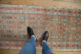 The distressed texture and earthy palette of a vintage Hamadan runner viewed from above for scale.