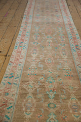 Angled view of a distressed runner's repeating Herati design with turquoise and cinnabar red accents.